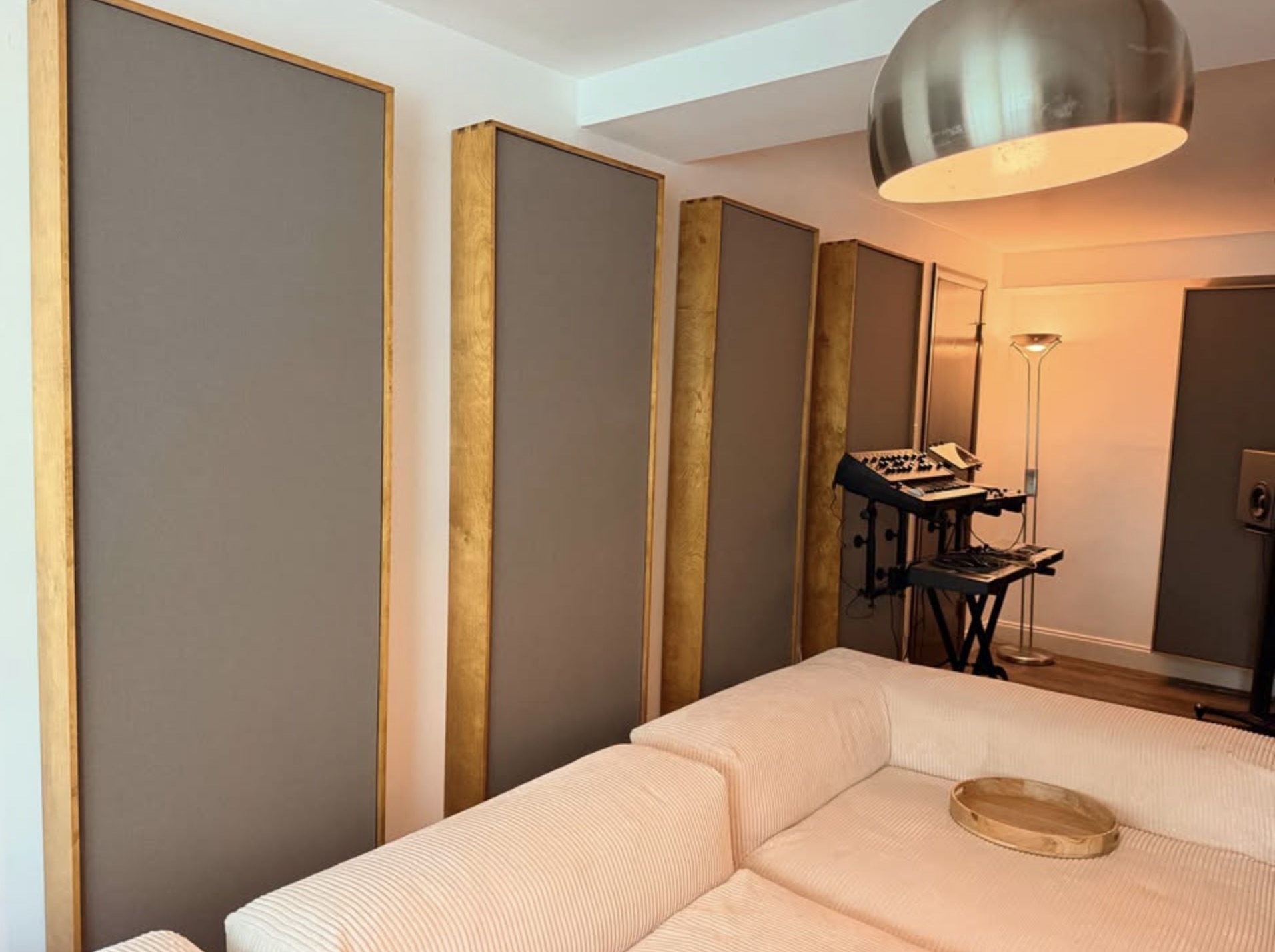 A row of tall burlap-wrapped acoustic panels in birch frames mounted along a studio wall.